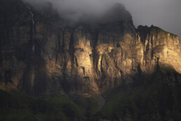 Soleil éclairant une falaise et une cascade en Haute Savoie