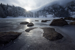 Lac gelé laissant apparaître des rochers dans les Hautes Vosges